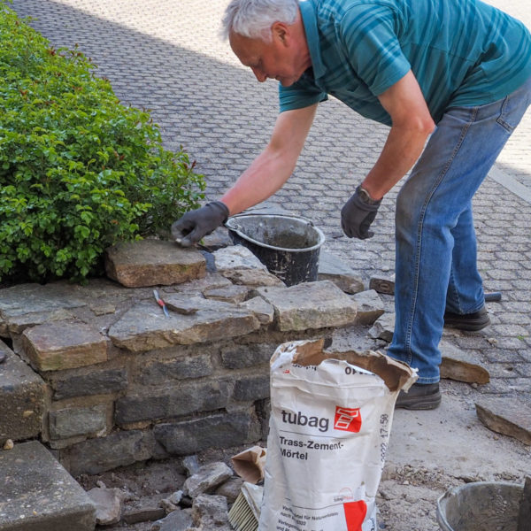 Rainer Lenz beim Ausbessern der Steinmauer an der Rosenrabatte.